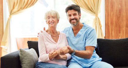 Smiling male nurse and elder woman on a couch